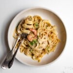 jerk shrimp pasta in a bowl with a fork twirled in noodles and a spoon.