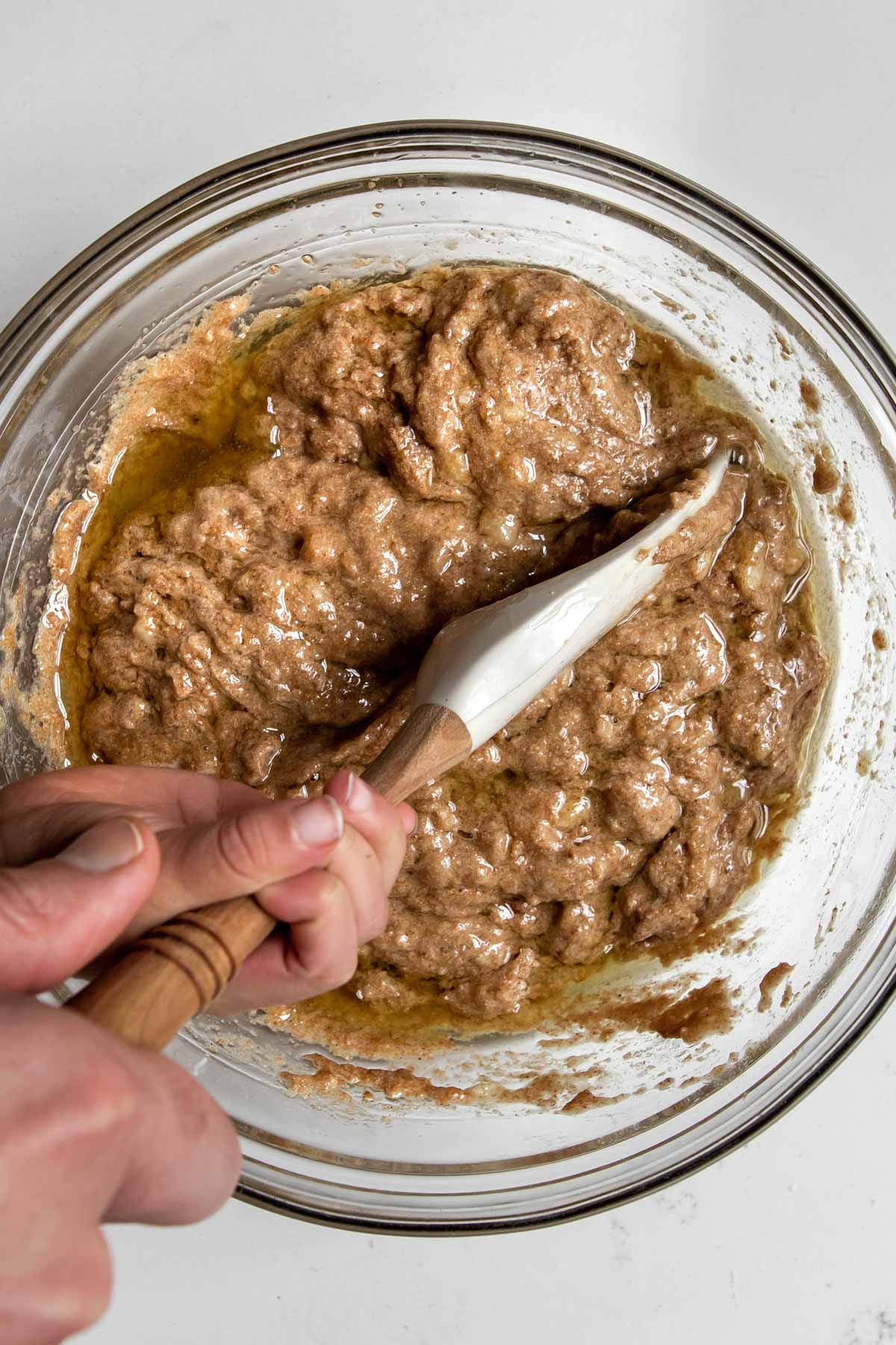 adult and child hands folding avocado oil into banana batter.