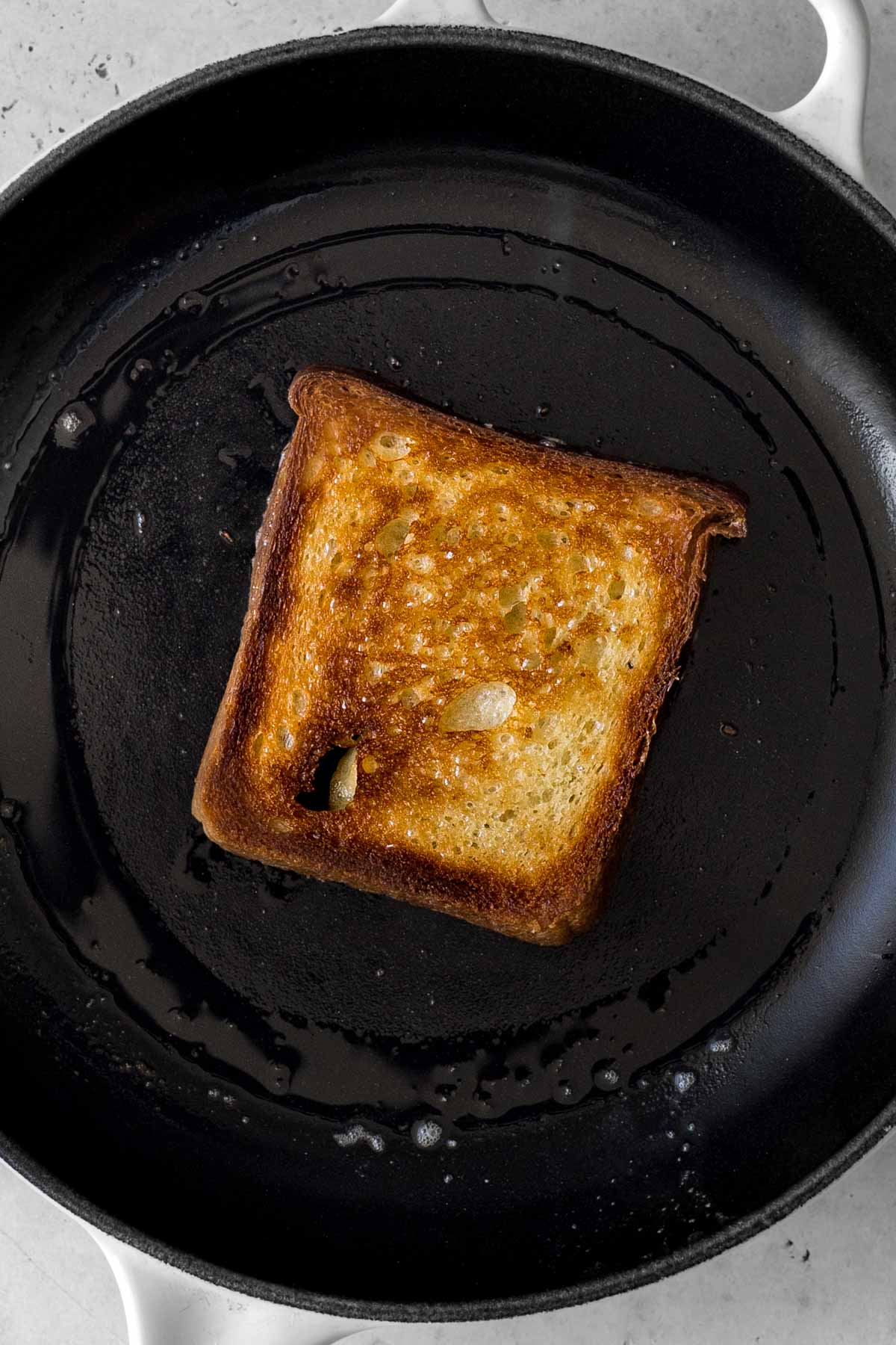 a piece of sourdough toast toasting in a skillet.