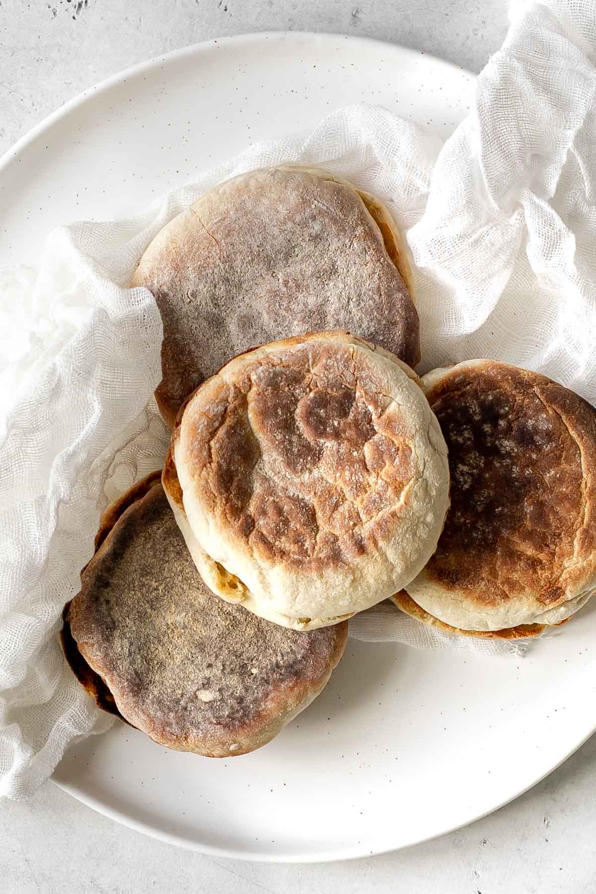 four toasted english muffins sitting on a plate.