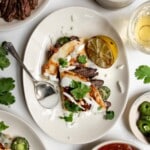 carne asada quesadillas on a plate topped with sour cream, cilantro and onions.