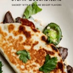 grilled carne asada quesadilla on a plate topped with cilantro.