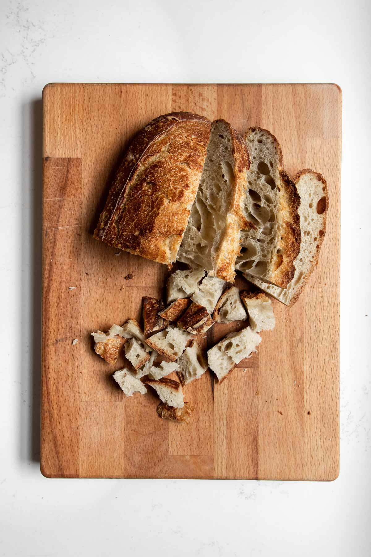 sliced and cubed sourdough bread on a cutting board.