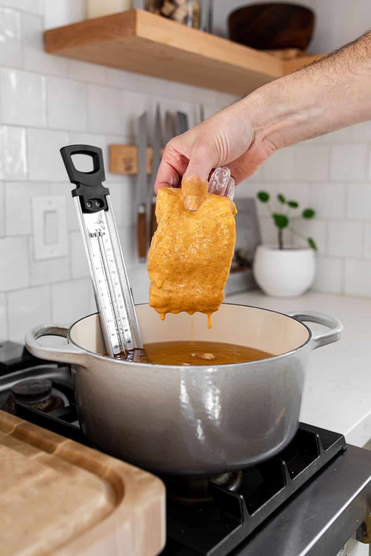 hand holding a dredged piece of cod oven hot oil.