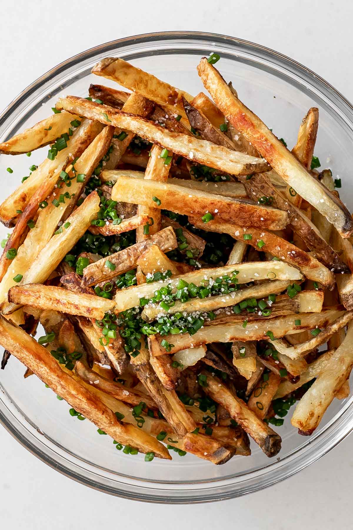 baked french fries in a bowl seasoned with chives and salt.