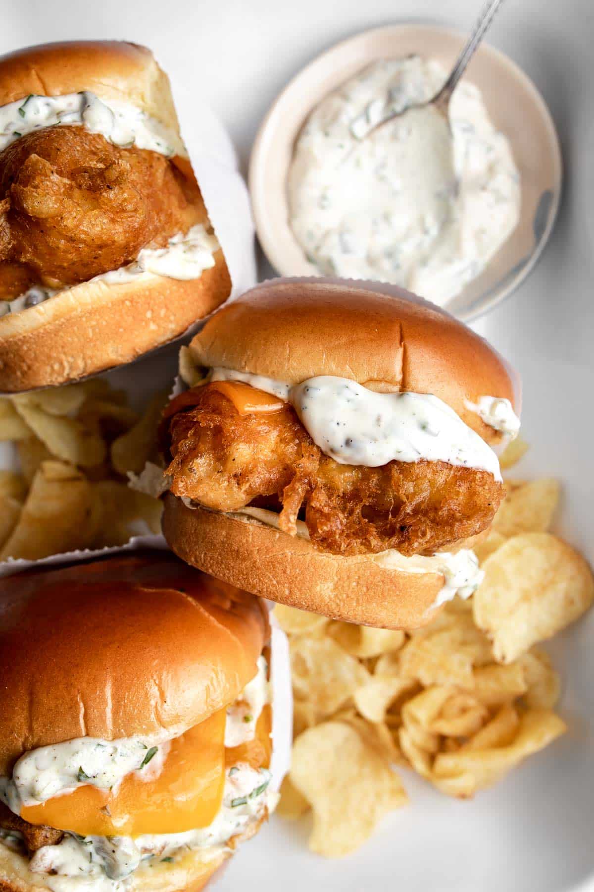 Three fried fish sandwiches (filet-o-fish) served with tartar sauce and chips.