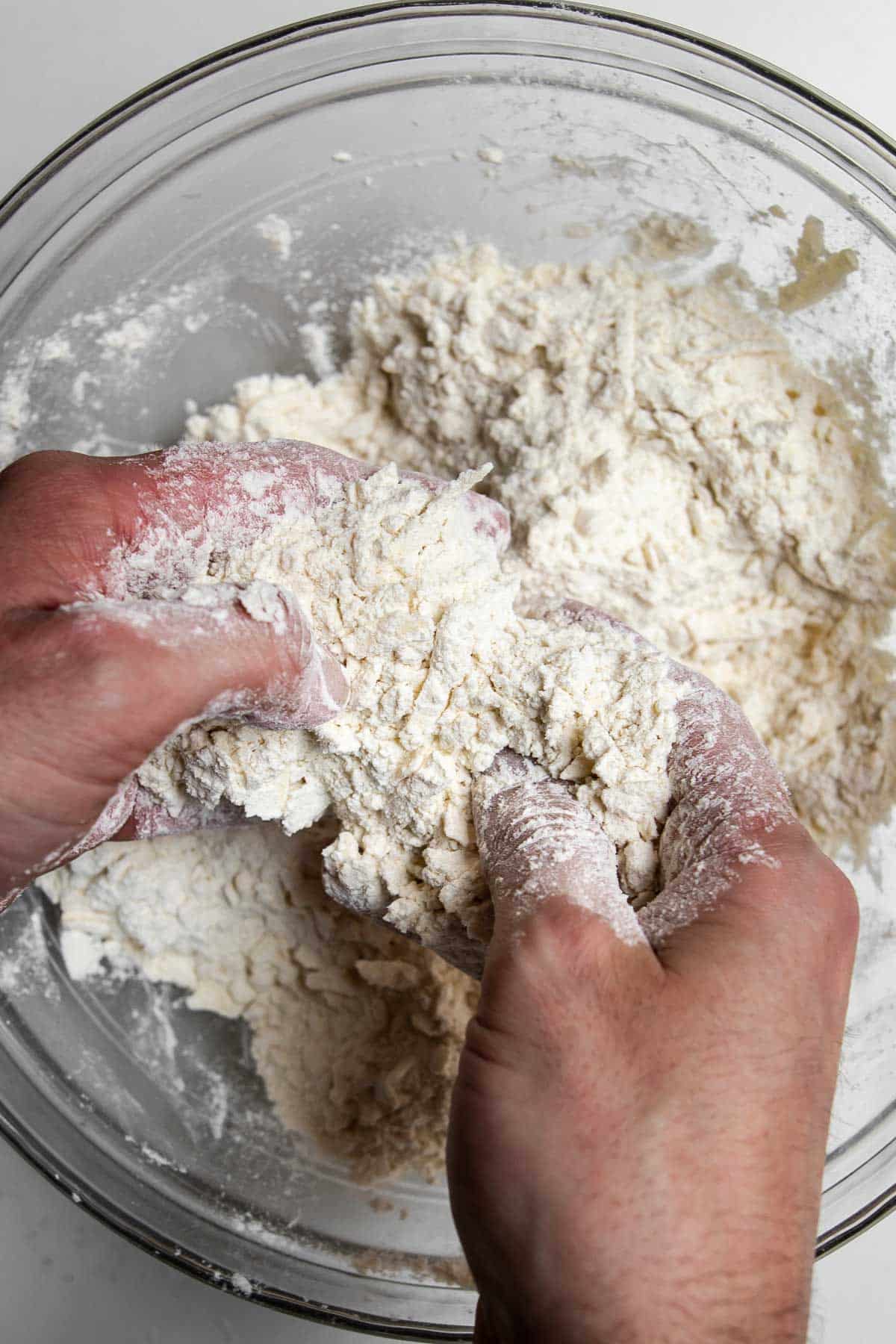 hands tossing grated butter in dry ingredients.