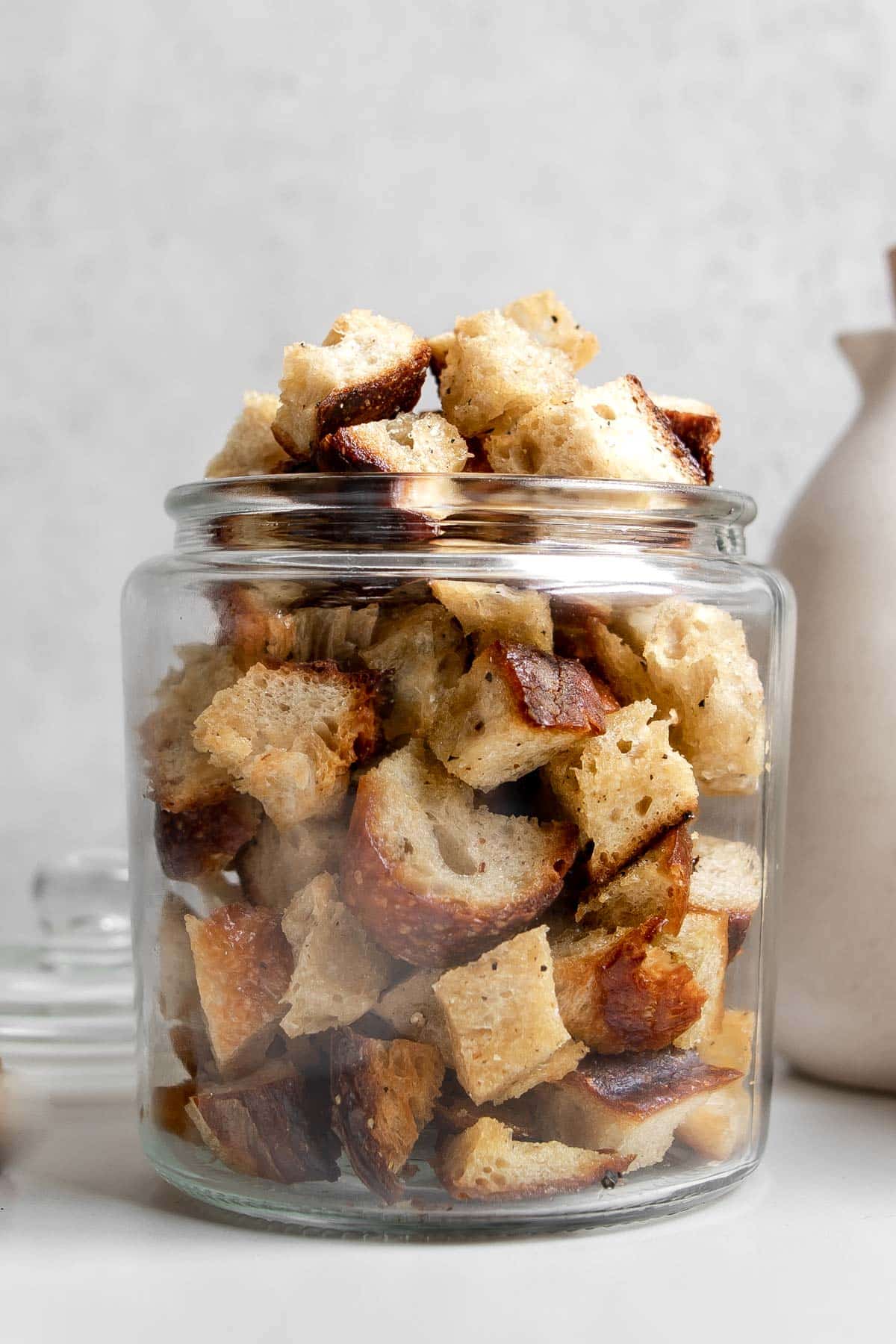 close up of sourdough croutons in a clear glass jar filled to the top.