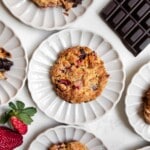 dark chocolate strawberry scone on a plate with scones, strawberries and chocolate around it.