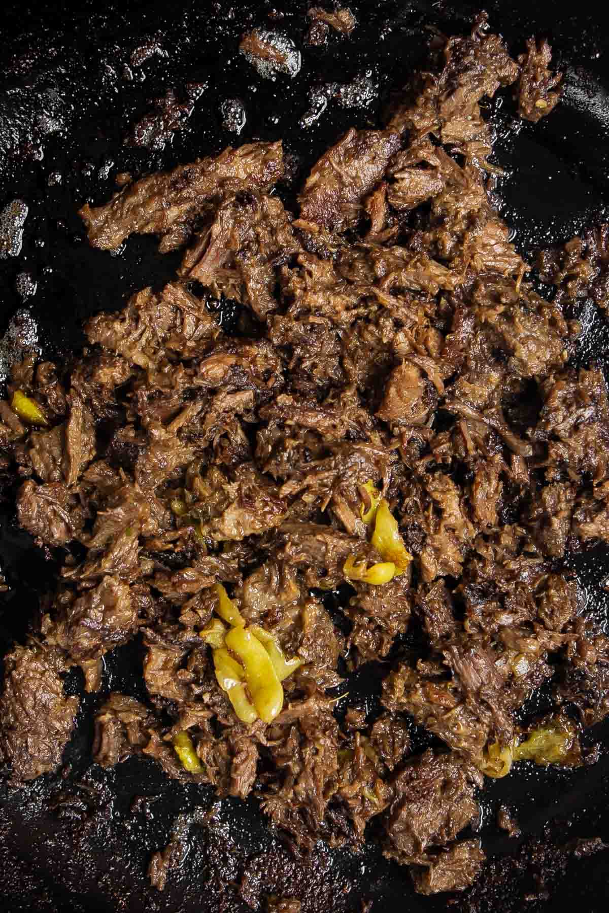 cooked Mississippi pot roast with pepperoncinis in a pan.