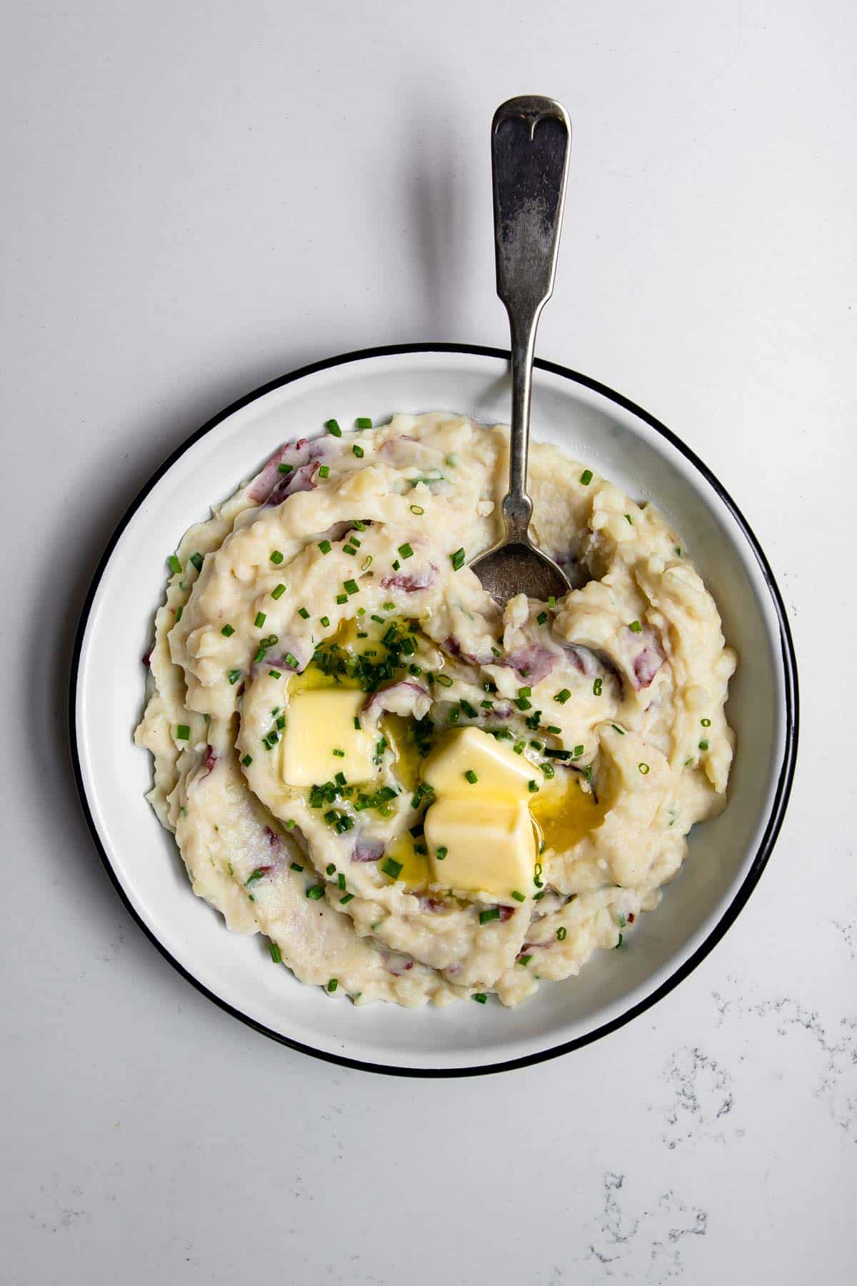 creamy red skin mashed potatoes with butter and chives in a bowl.