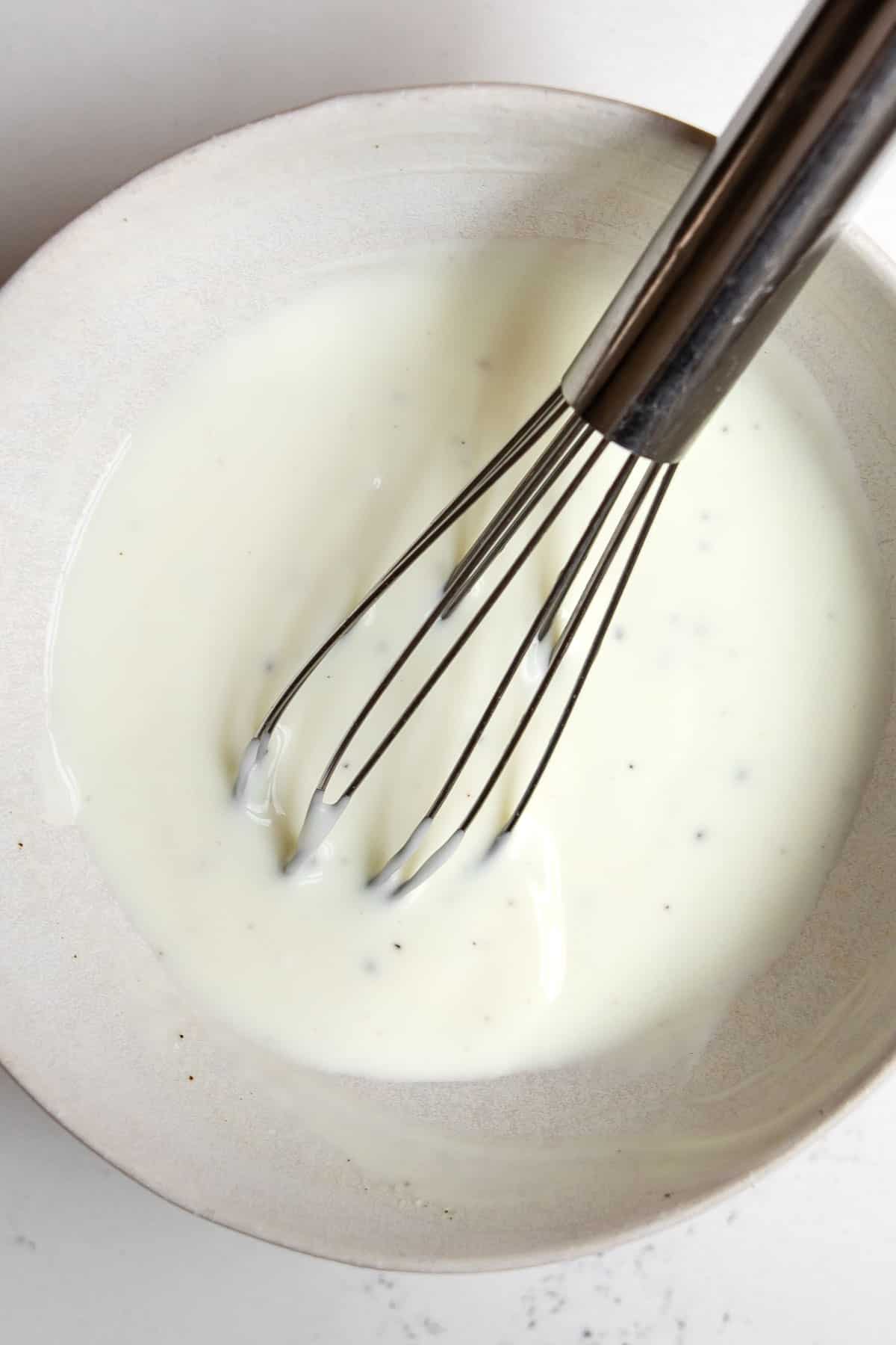 sour cream and pepperoncini juice in a bowl with a whisk.