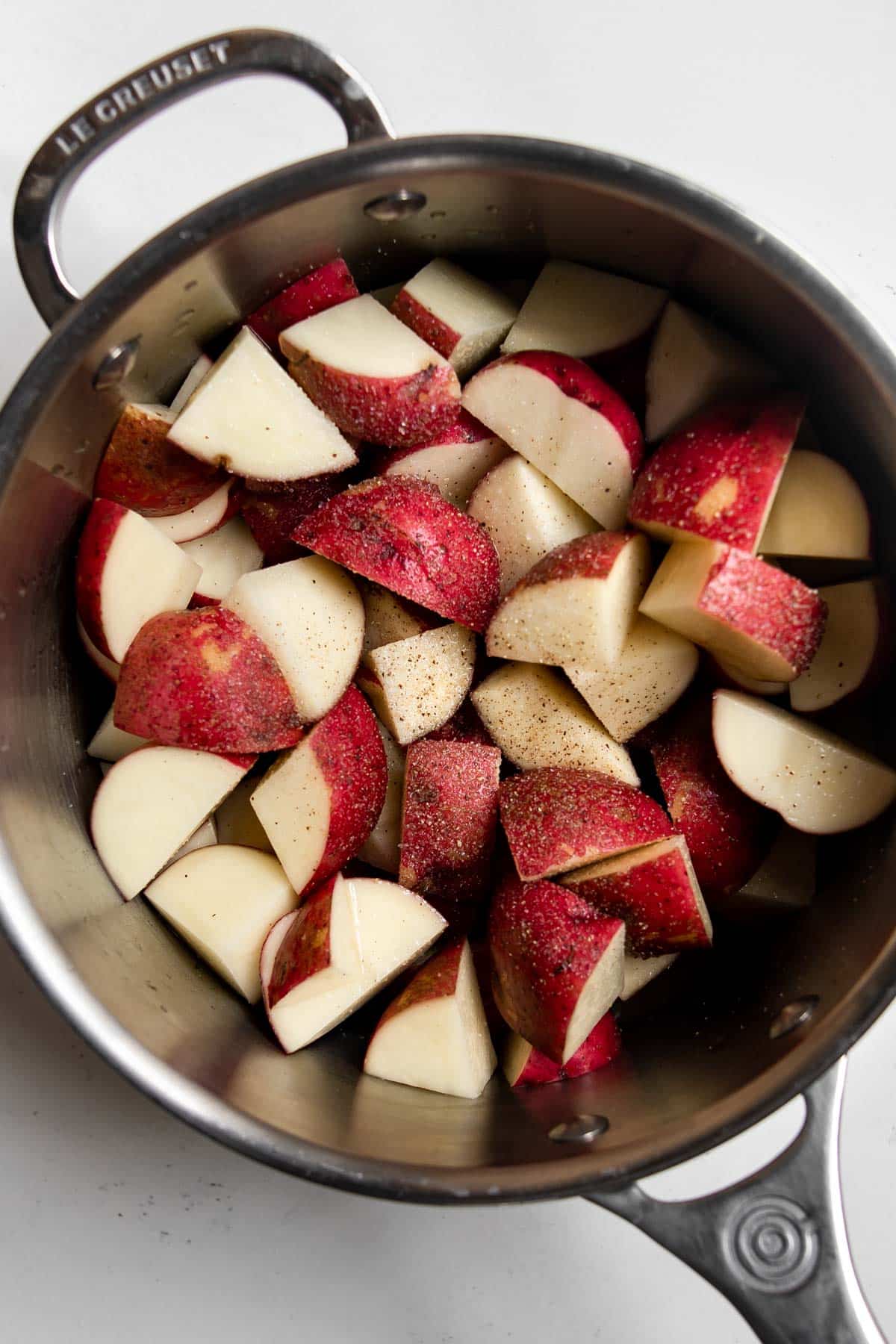 cut red skin potatoes in a pot.