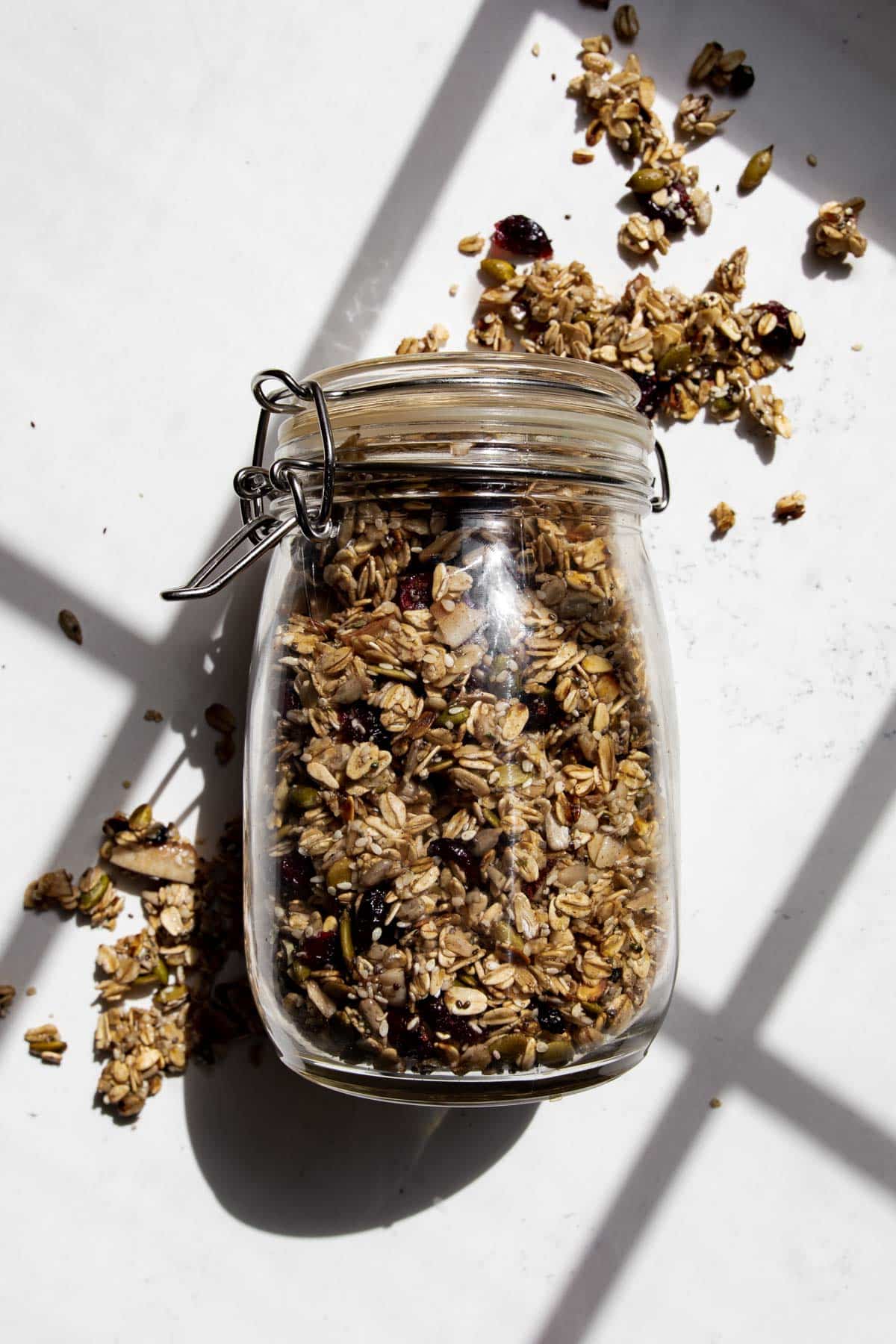 nut free granola in a jar laid out on the counter with granola around it.