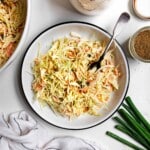 sweet coleslaw in a bowl with ingredients around it.