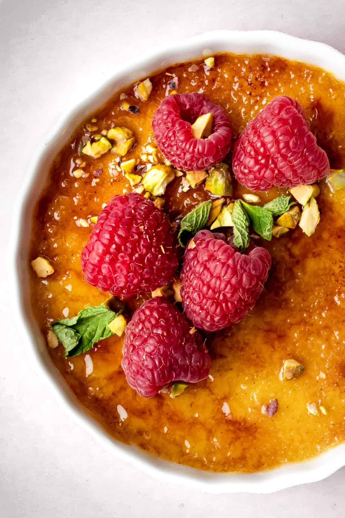 coconut crème brûlée topped with raspberries, pistachios and mint.