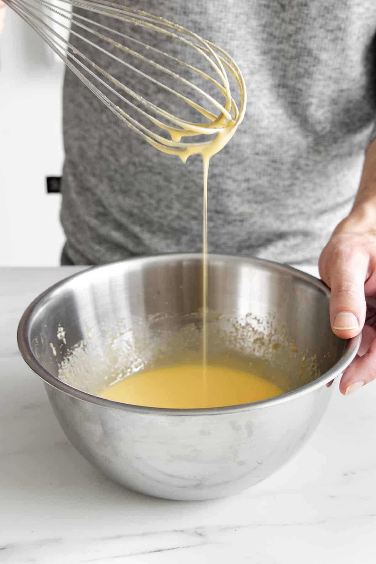 bowl with coconut custard with a whisk showing smooth consistency.
