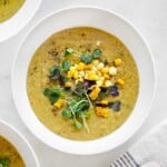 dairy-free corn chowder with coconut milk in a bowl garnished with corn and sprouts.