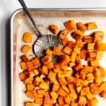 frozen roasted butternut squash on a sheet pan with a serving spoon.
