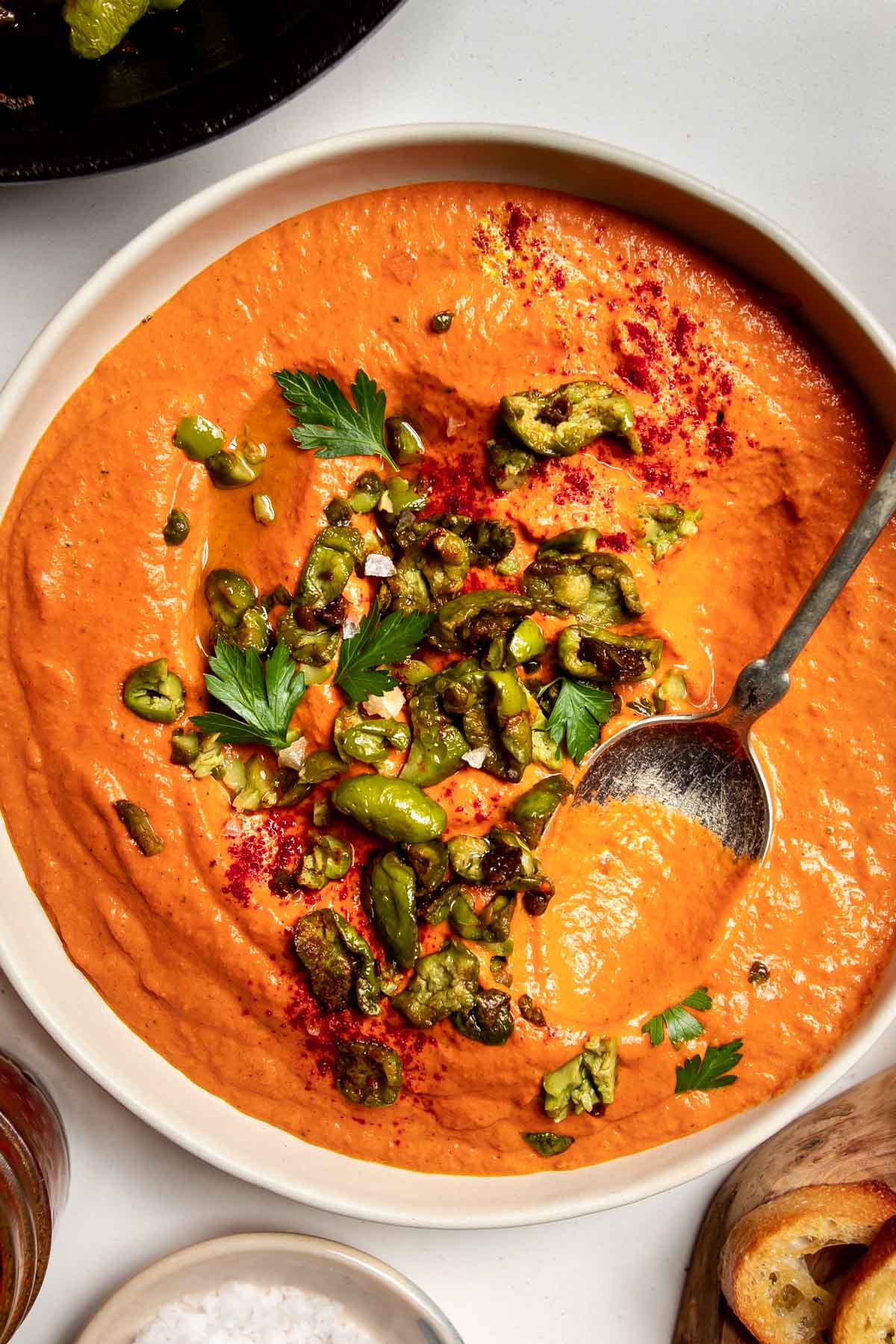 roasted red pepper dip with olives on a plate with a spoon.