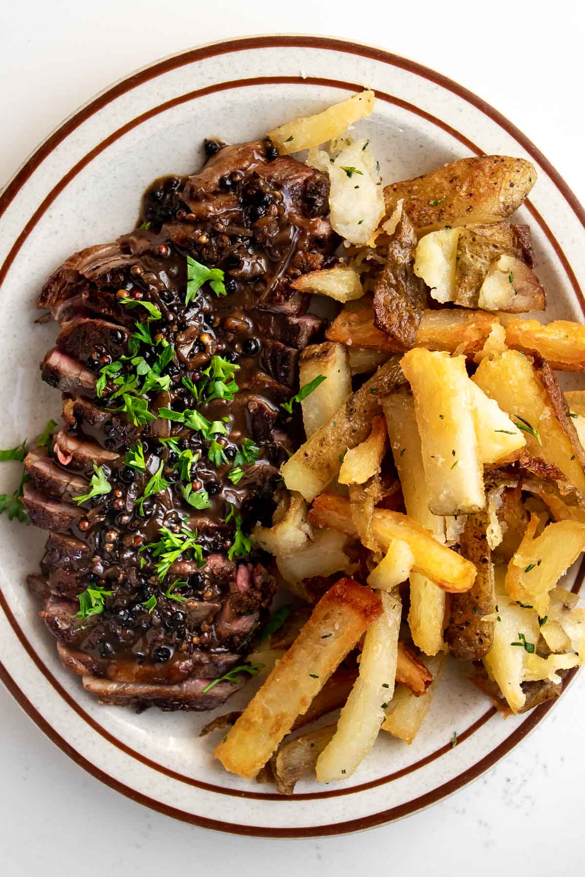 sirloin steak cut up on a plate with french fries