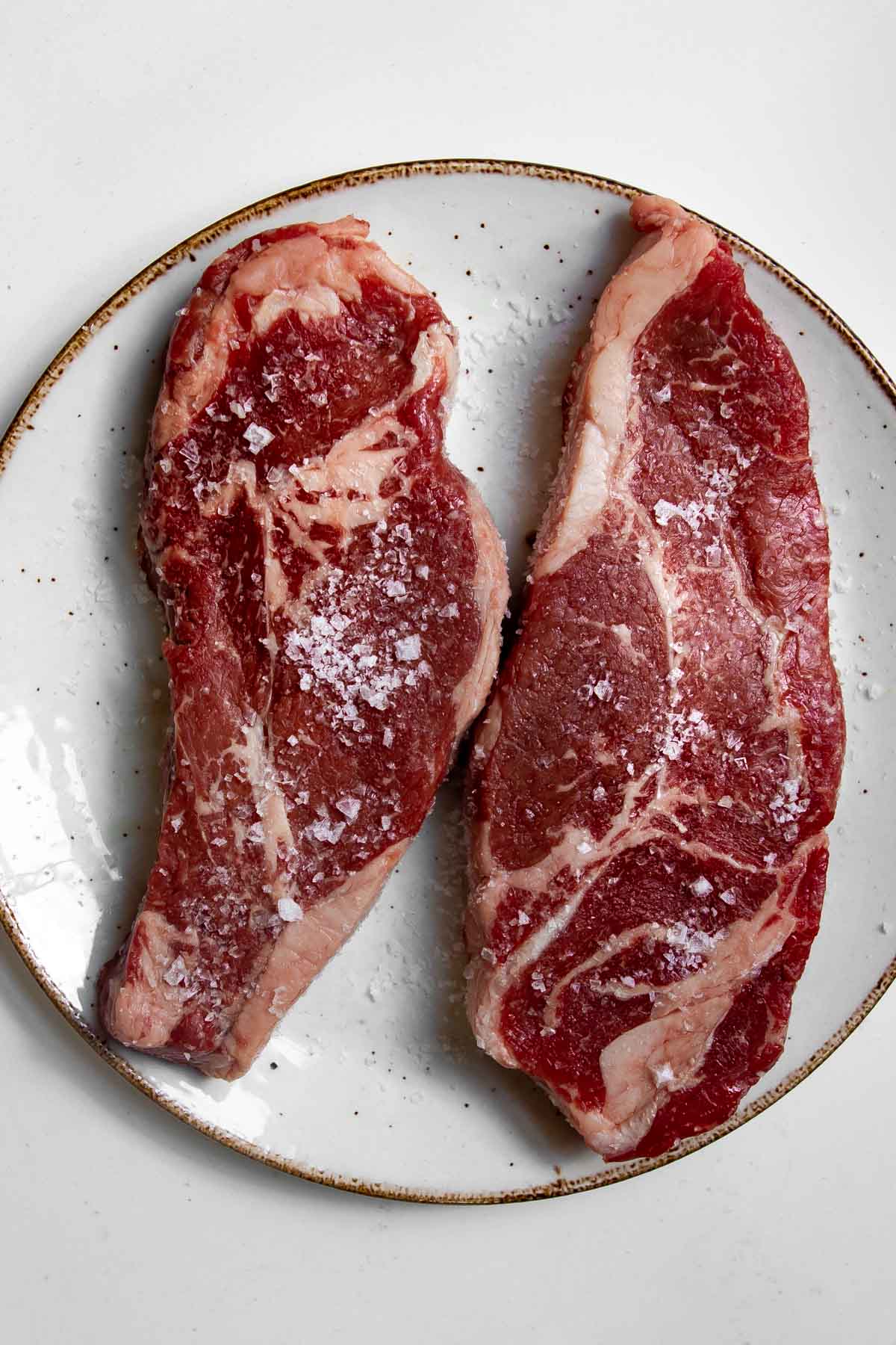 sirloin steaks on a plate seasoned with salt