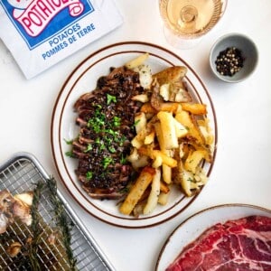 sirloin steak cut up on a plate with french fries