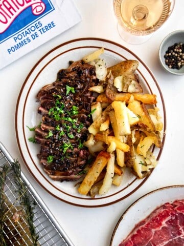 sirloin steak cut up on a plate with french fries